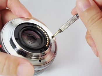 Close-up of hand holding camera over white background
