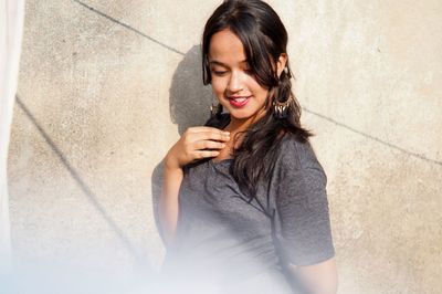 Smiling young woman standing against wall
