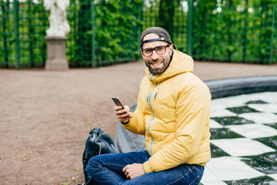 Young man using mobile phone while sitting outdoors