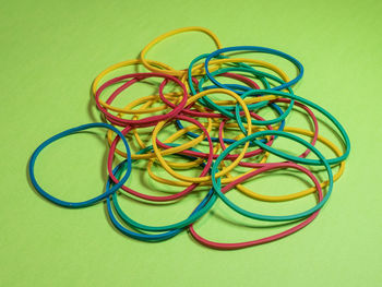 Close-up of multi colored rubber bands against green background