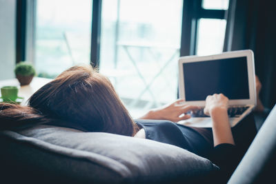 Rear view of woman using mobile phone at home