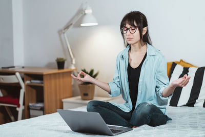 Frustrated young woman gesturing by laptop in office