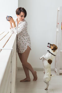 Woman with dog standing on mobile phone