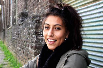 Portrait of smiling young woman sitting against wall