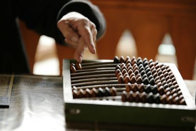 Midsection of man playing with abacus at table