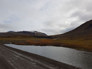 Scenic view of lake by mountain against sky