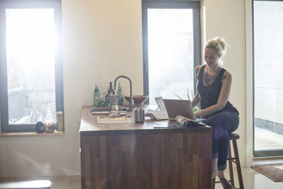 Woman using mobile phone while sitting on table