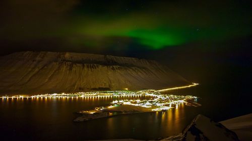 Illuminated commercial dock by sea against sky at night