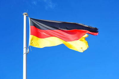 Low angle view of flag against blue sky