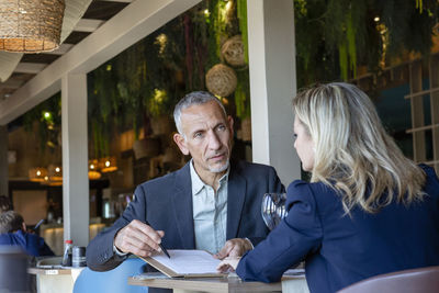 Businessman explaining contract to client sitting in restaurant