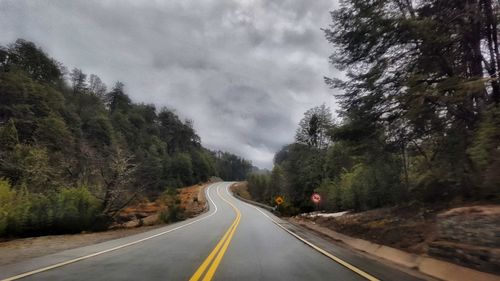 Road amidst trees against sky