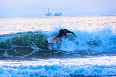 Man surfing in sea against sky