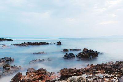 Scenic view of rocks in sea against sky