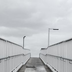 Footpath leading towards bridge against sky