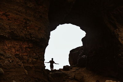 Low angle view of woman standing amidst rock formation