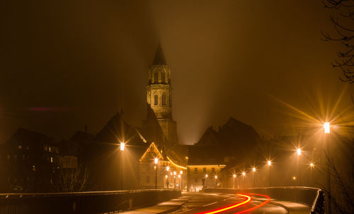 Light trails on road against buildings at night