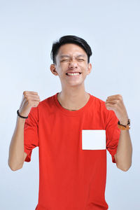 Young asian man happy and excited expressing winning gesture. successful and celebrating