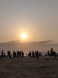 Silhouette people on beach against sky during sunset