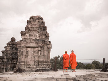 Rear view of monks standing by built structure
