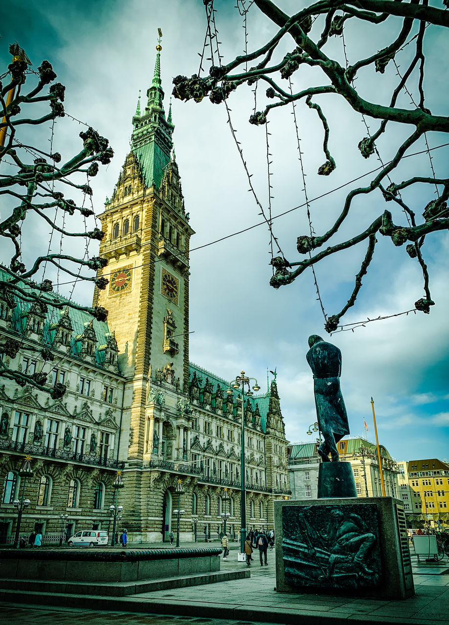 LOW ANGLE VIEW OF CLOCK TOWER AGAINST BUILDINGS