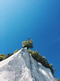 Low angle view of rocks against clear blue sky