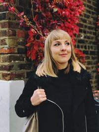 Portrait of beautiful young woman standing against red wall