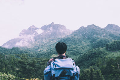 Rear view of man looking at mountains against sky