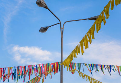 Low angle view of multi colored flags hanging against sky