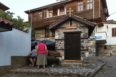 Rear view of woman walking on alley amidst buildings