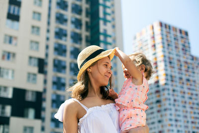 Young woman wearing hat standing against buildings in city