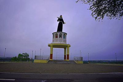 Low angle view of lighthouse by building against sky