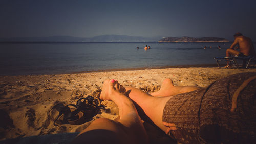 Low section of man and woman relaxing on beach