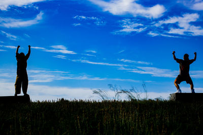 Silhouette people standing on field against sky