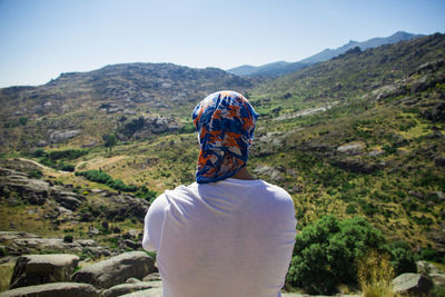 Rear view of man standing on mountain against sky