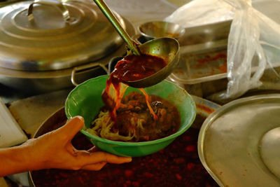 Close-up of hand serving food in bowl