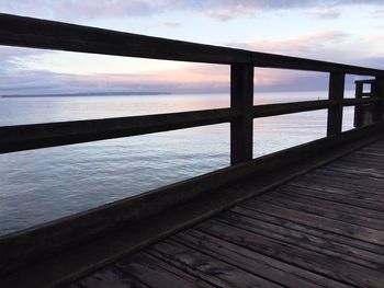 Pier on sea against cloudy sky