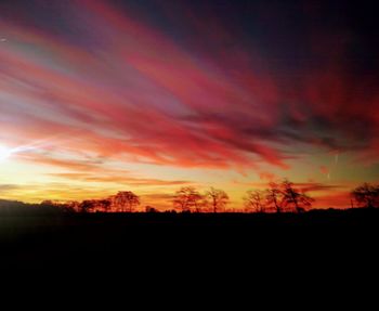 Silhouette landscape against dramatic sky during sunset