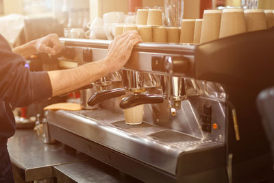 Midsection of barista preparing coffee in cafe