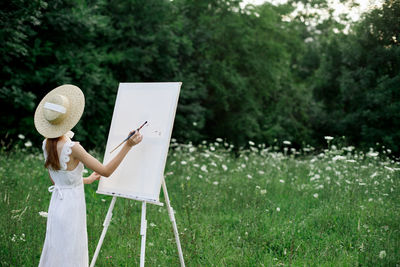 Woman holding umbrella while standing against plants