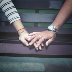 Cropped image of couple holding hands on bench