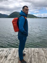 Young man standing on lake against sky