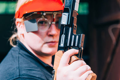 Close-up portrait of woman holding gun