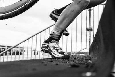 Low section of person by railing against sky