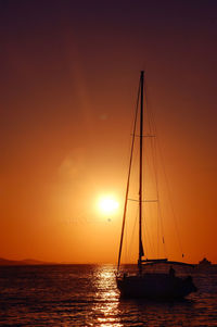 Sailboat sailing in sea at sunset