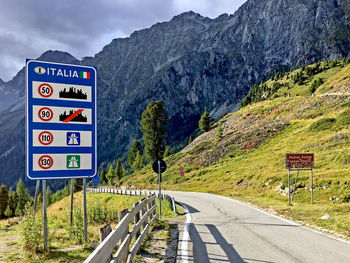 Road sign by mountains against sky