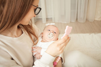 Mother plays with newborn baby, little girl explores world, looks at toy. early 