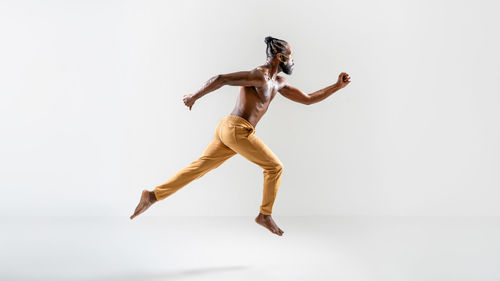 Full length of man jumping against white background