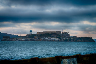 Buildings by sea against sky at dusk