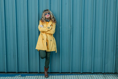 Full length of woman standing against blue wall