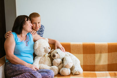 Kid plays with an old grandmother and teddy bear toy. cheerful and smiling